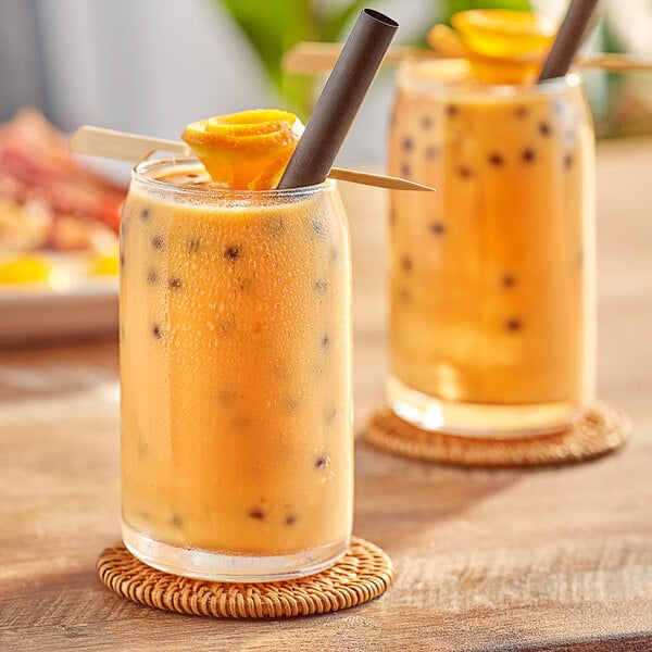 Two glasses of Fanale orange syrup with straws and a fruit slice on a table