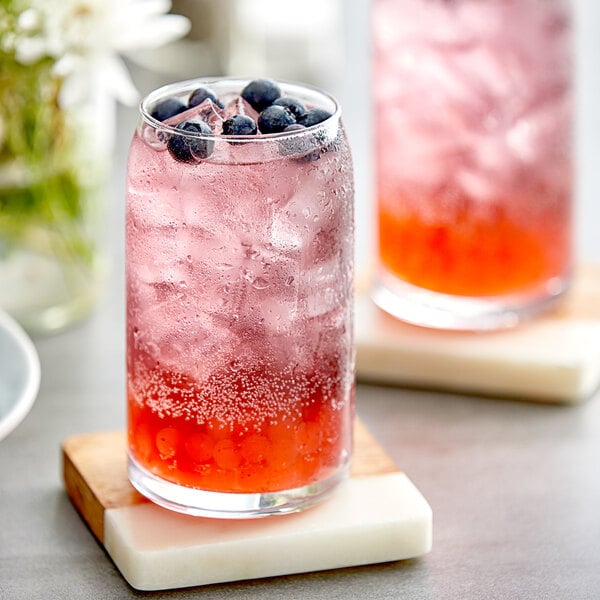 A glass of Fanale blueberry syrup mixed with ice and lemonade with blueberries.