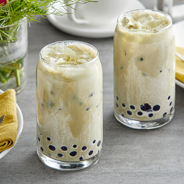 Two glasses of Fanale matcha bubble tea with black bubbles on a table.