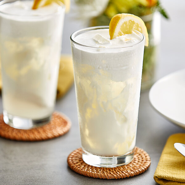 A glass of white liquid with Fanale Lemon syrup and a lemon wedge.