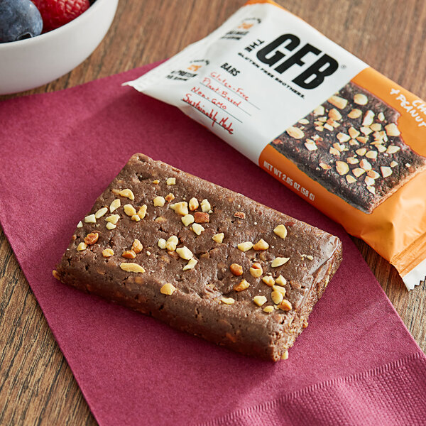 A GFB chocolate bar with nuts on top next to a bowl of berries.