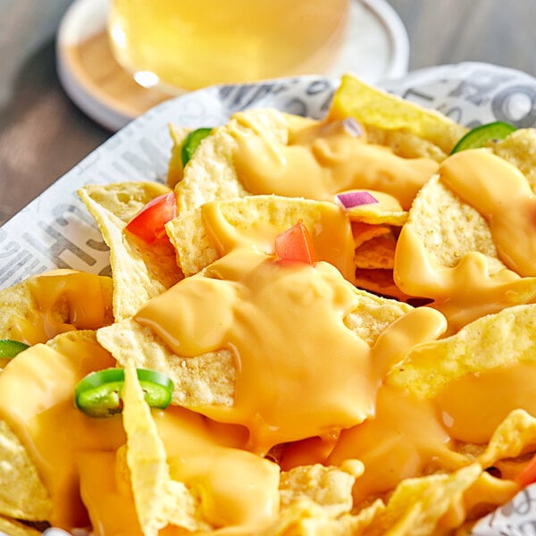 A plate of nachos with Muy Fresco vegan cheese sauce and jalapenos.