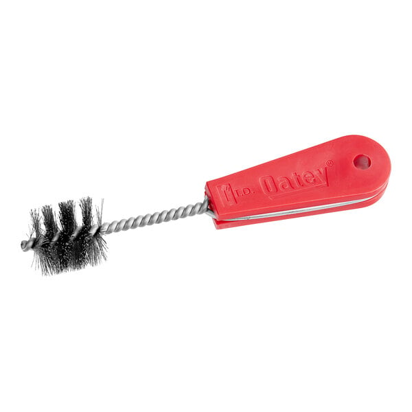 A close-up of a red Oatey fitting brush with a metal handle.