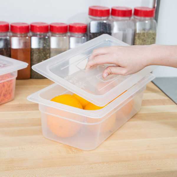 A hand using a Cambro translucent polypropylene lid to cover a plastic food container.