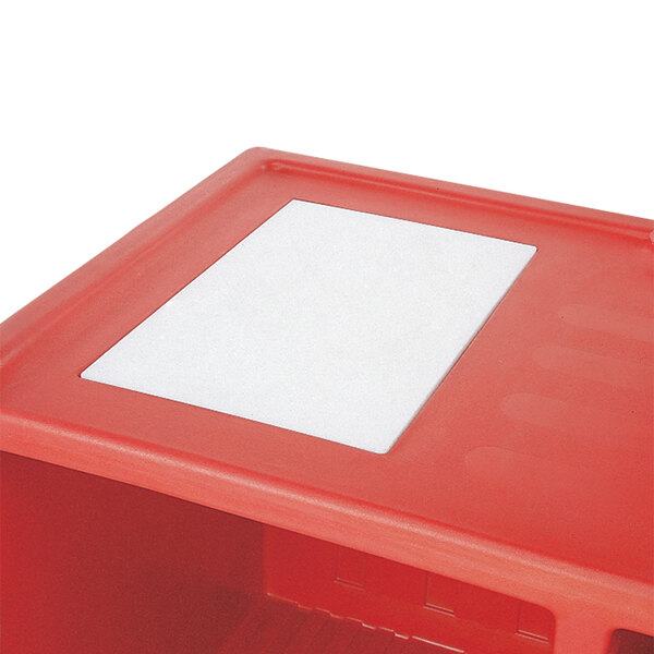 A red plastic box with a white rectangular cutting board inside.