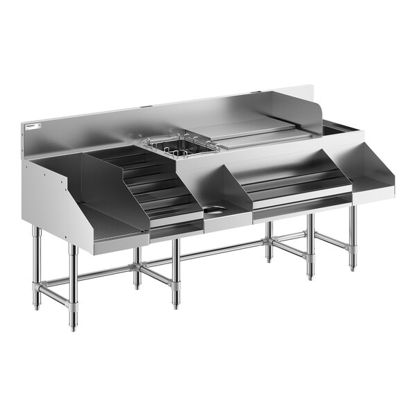 A large stainless steel commercial cocktail station with multiple compartments, a liquor display rack, and a drainboard, supported by metal legs.