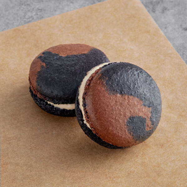 Two Macarons, one with chocolate and black spots, on a table.