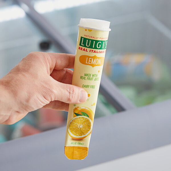 A hand holding a yellow Luigi's Lemon Italian Ice tube.