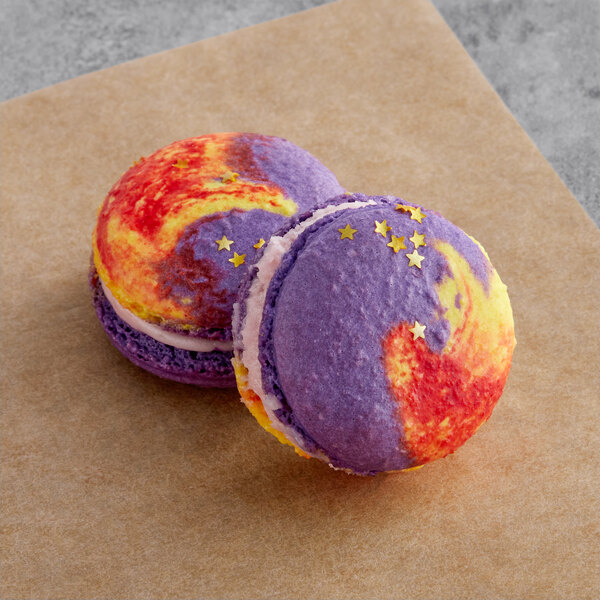Two colorful macarons, one purple and one yellow, with colorful designs on them.
