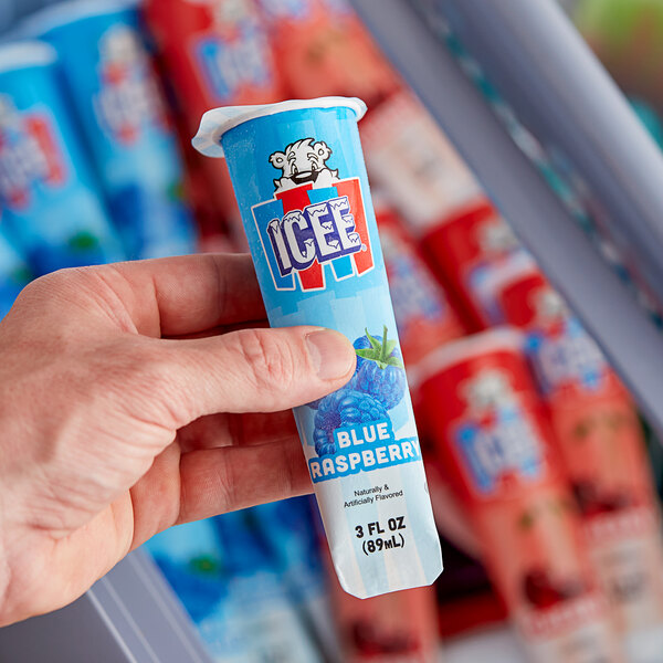 A hand holding a blue and red ICEE Freeze tube package.