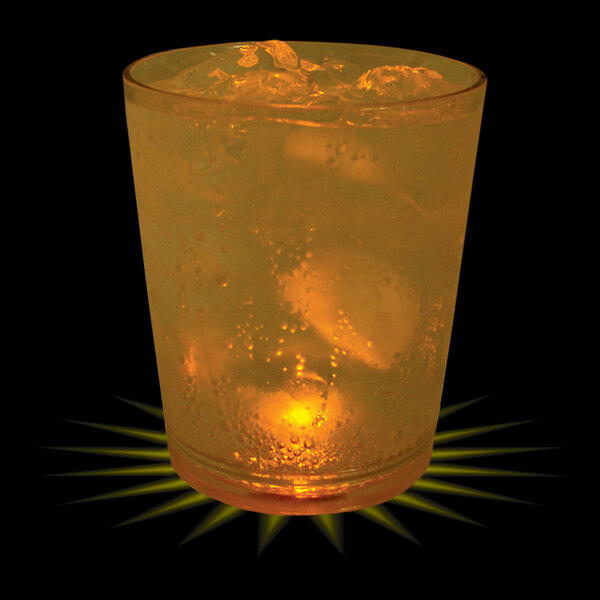 A customizable plastic rocks cup with ice and orange liquid with a yellow LED light in it.