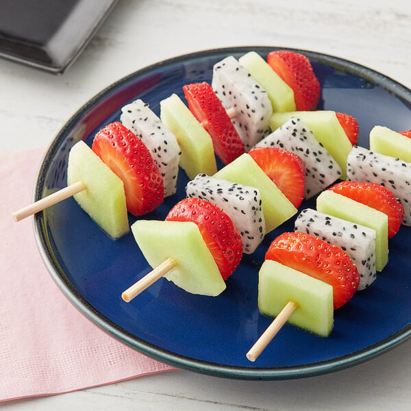 A plate of fruit skewers with strawberries and kiwi on wooden skewers.