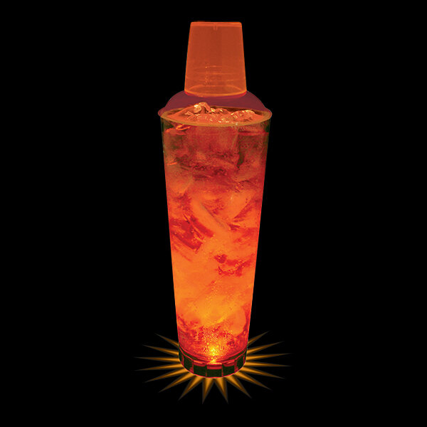 A customizable plastic cocktail shaker with orange LED lights on a glass of orange liquid.