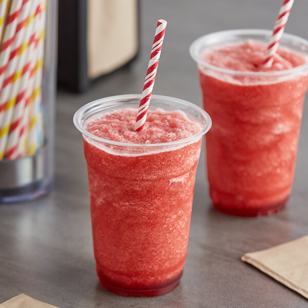 Two plastic cups of red Original Slushie Company cherry slushies with straws.