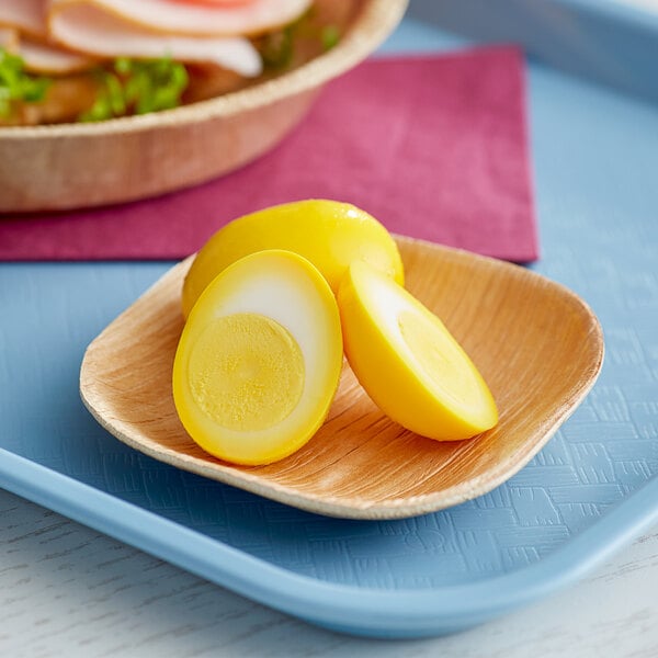 A plate with sliced Martin's Quality yellow hard cooked eggs on a table.
