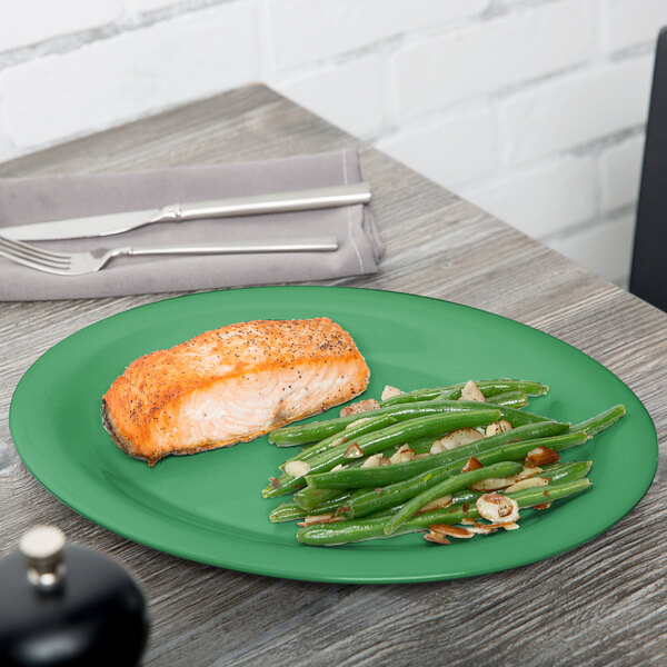 A GET rainforest green oval melamine platter with salmon and green beans on it.