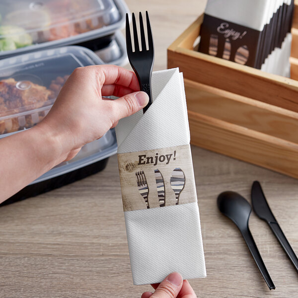 A hand holding a napkin with a fork and knife.
