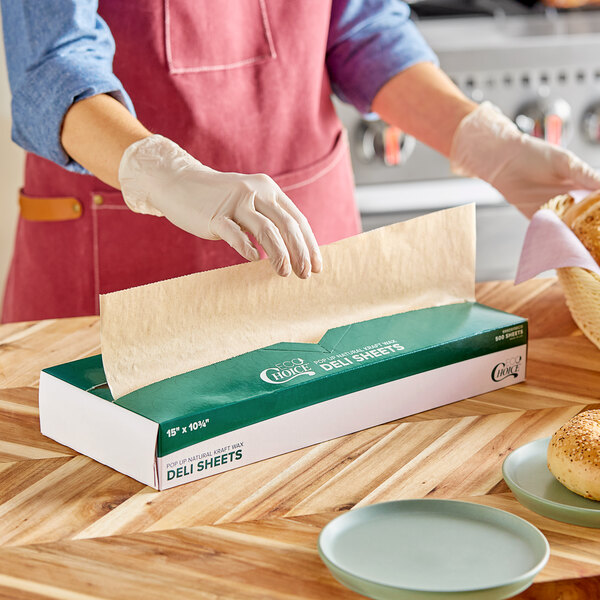 A person wearing gloves in a professional kitchen using EcoChoice natural kraft deli wrap to prepare bread.