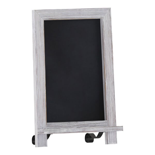 A whitewashed wooden tabletop chalkboard with metal scrolled legs.