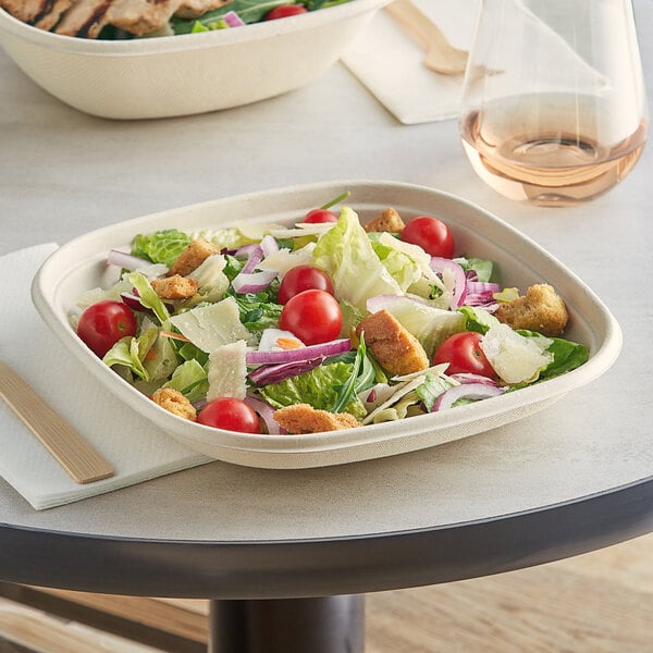 A salad in a World Centric compostable square fiber bowl with a wooden fork.