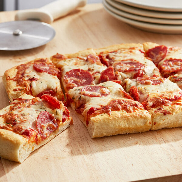 A square pizza with pepperoni and cheese on a wood surface.