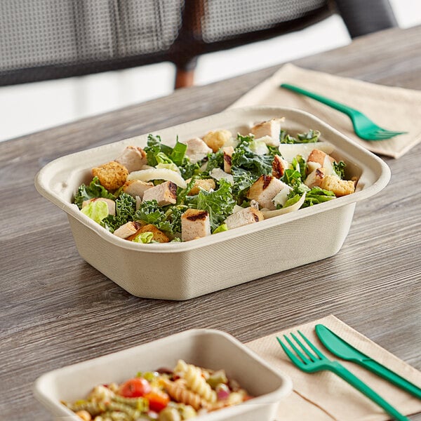 A World Centric compostable fiber container filled with salad on a table.