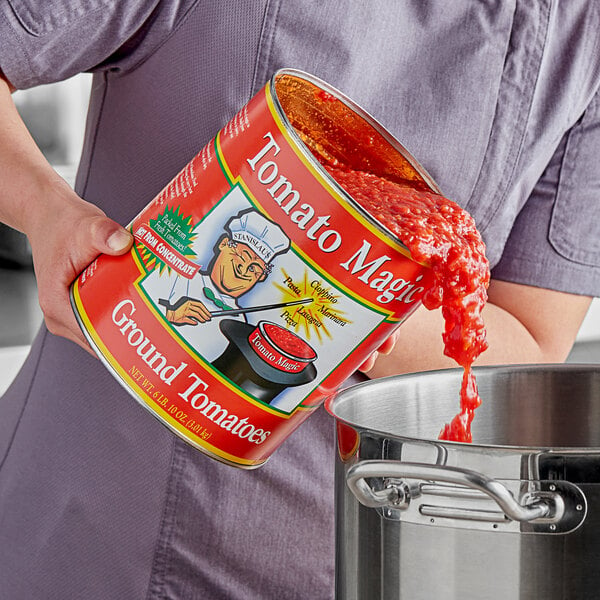 A person pouring Stanislaus Tomato Magic ground peeled tomatoes into a pot.