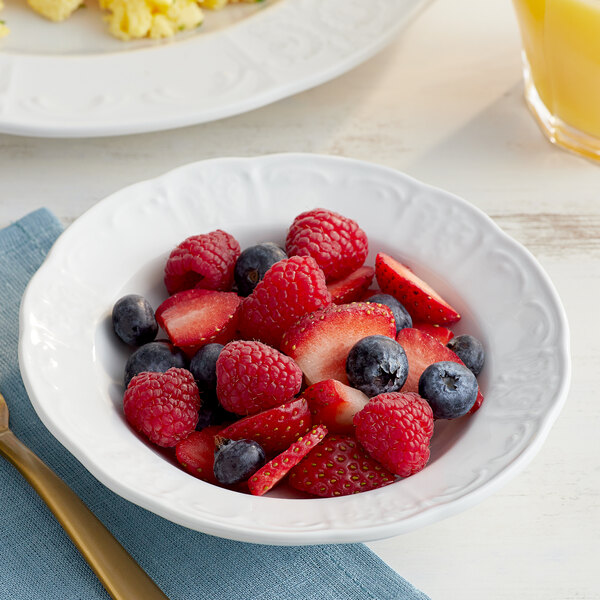 A Tuxton bright white china monkey dish filled with strawberries and blueberries.