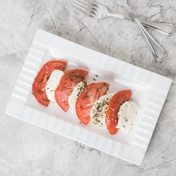 A CAC Queensquare rectangular porcelain platter with tomatoes and mozzarella on it.