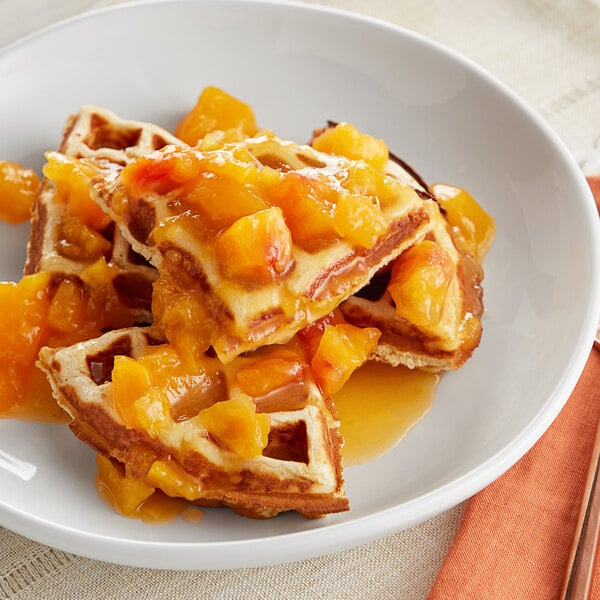 A plate of waffles with Oregon Fruit peach topping and fruit.
