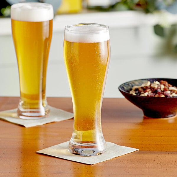 Two Acopa Pilsner glasses of beer on a table.
