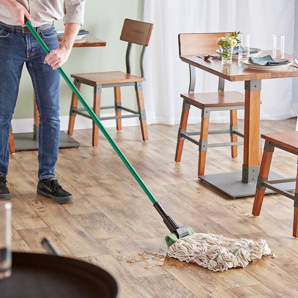 A person mopping the floor with a Lavex mop with a green handle.
