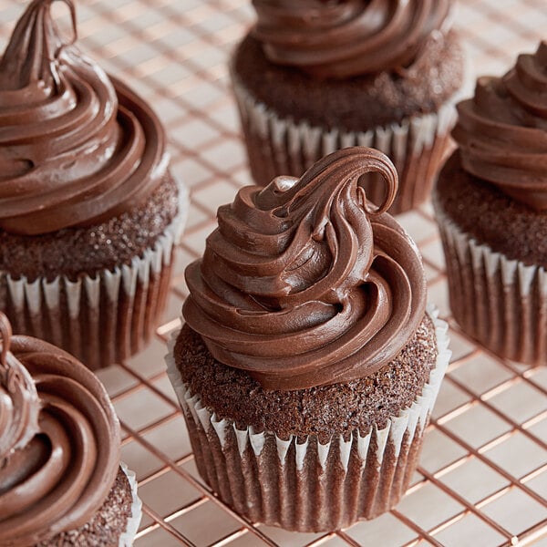 A group of chocolate cupcakes with chocolate frosting on a cooling rack.