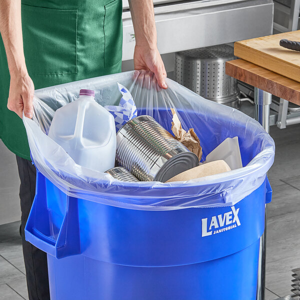 A woman holding a clear plastic bag full of trash.