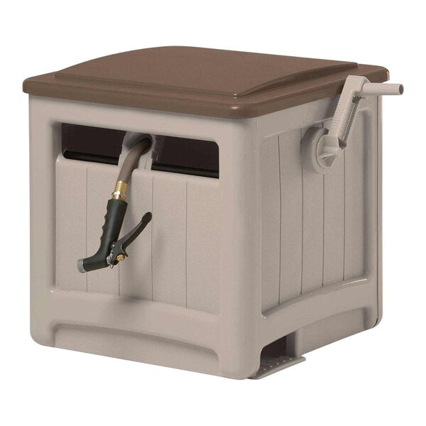 A brown and tan Suncast Smart Trak hose storage hideaway box on a table with a plastic hose reel and hose coming out of it.