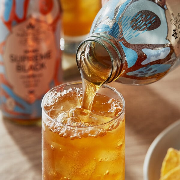 A Harney & Sons glass bottle pouring organic black iced tea into a glass.