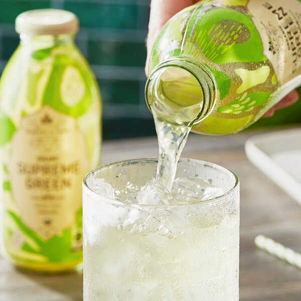 A person pouring Harney & Sons Organic Supreme Green Unsweetened Iced Tea into a glass of ice.