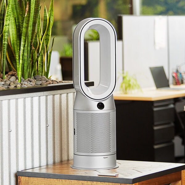 A white and silver Dyson Purifying Fan and Heater on a table.