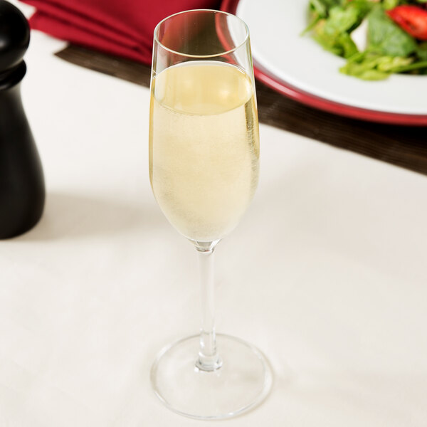 A Stolzle flute glass filled with champagne on a table.