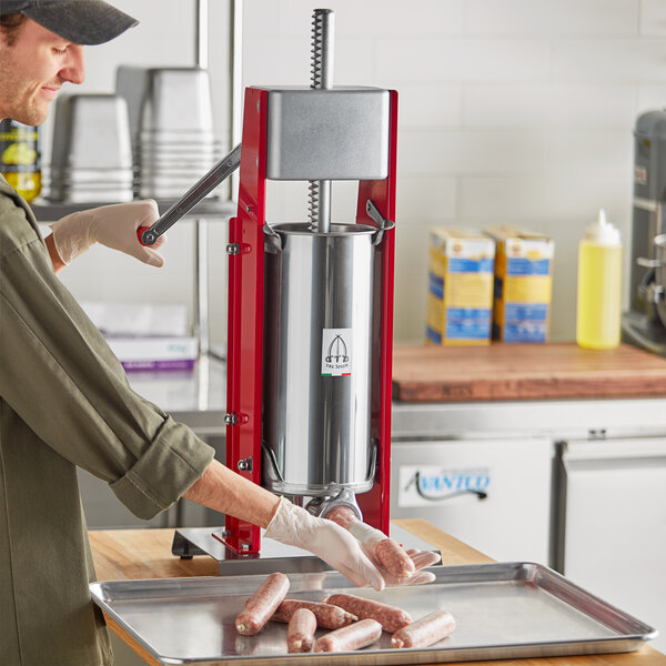 A woman using a Tre Spade manual sausage stuffer on a butcher shop counter.