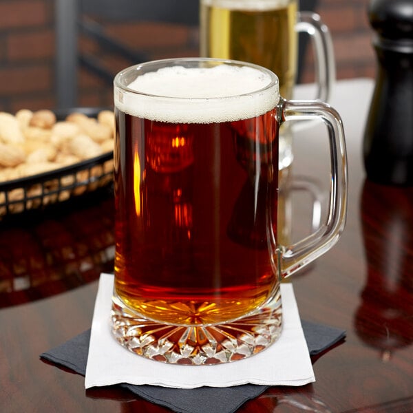 A Libbey glass mug of beer on a napkin.
