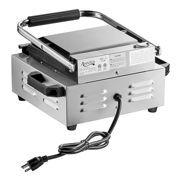 An Avantco commercial panini grill with grooved top and smooth bottom plates, silver and black with a cord attached.