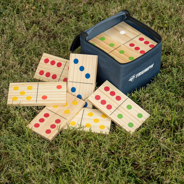 A blue bag with a Yard Games Giant Wooden Domino Set on grass.