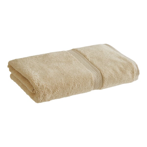 A folded beige Magnificence Pima Cotton bath sheet.