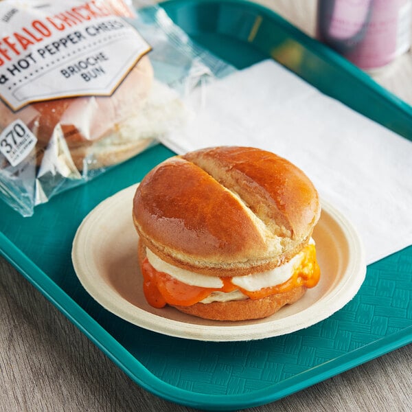 A tray with a Grand Prairie Buffalo Chicken Sandwich on a plate and a bag of chips.
