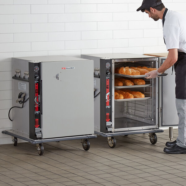 A man using a Metro TC90BB heated holding cabinet to load bread.