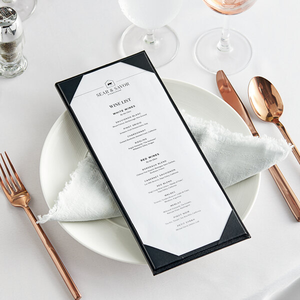 A black menu board on a white plate with silverware and a napkin.