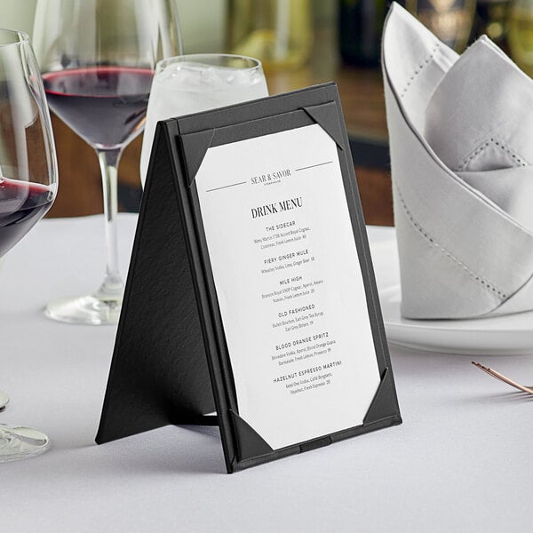 An Acopa Prime black 2-view table tent on a table with a menu and wine glasses.