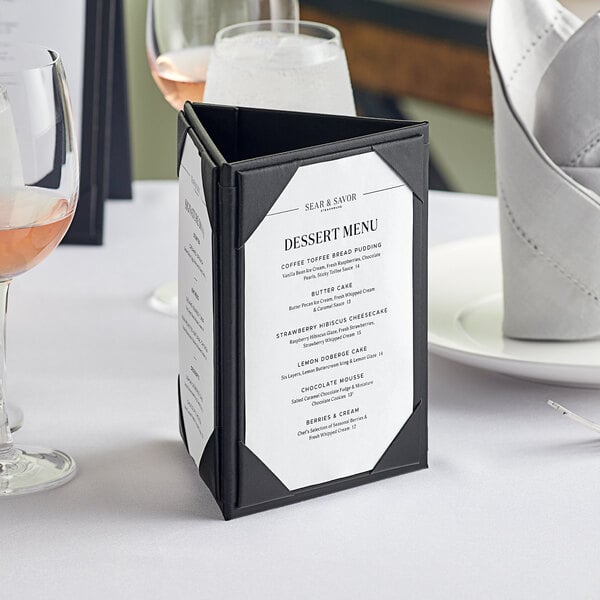 A black Acopa Prime triangular table tent on a white table with a menu.