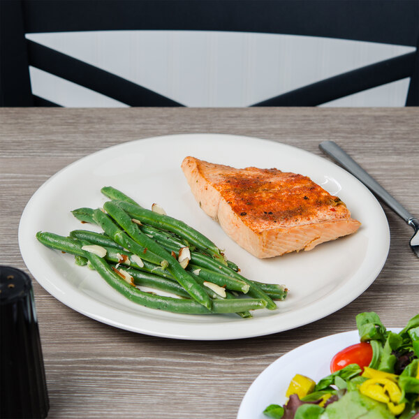 A plate of food with a piece of cooked salmon, green beans, and a tomato on a Carlisle Sierrus melamine plate.